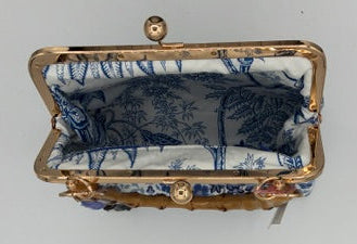 A vintage-style small handbag or clutch with a blue and white toile patterned fabric lining and a gold-tone metal frame, shown from the inside against a plain light background.