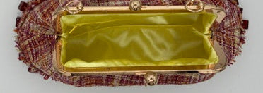 A small tweed clutch bag with a gold-tone frame and a shiny yellow satin interior, shown from above on a white surface.