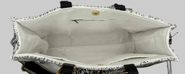 Top-down view of a white tweed tote bag with black trim and a white fabric lining, showing the interior structure and a gold-tone snap button closure.