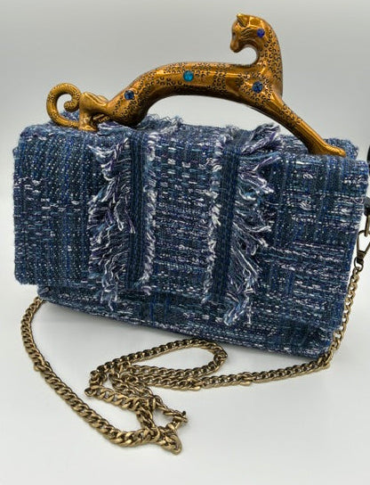 A blue tweed shoulder bag with a gold leopard-shaped handle and a gold chain strap, photographed from above on a light gray background.
