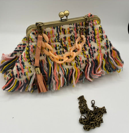 A multicolor fringed clutch purse with a gold-tone kiss-lock clasp, peach chain handle, and a separate antique bronze chain accessory on a white background.