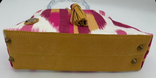 A handbag shown from the bottom side, featuring a tan leather base, brass studs, and a patterned top panel with pink, purple, and yellow stripes on a white background.