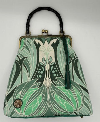 A vintage style Art Nouveau style handbag with a green and white floral pattern, a black acrylic bamboo handle, and a gold-tone metal frame, shown on a white background.