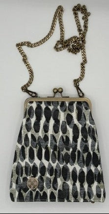 A small crossbody kiss-lock handbag with a black and white abstract patterned body and an antique bronze chain strap, shown against a plain light background.