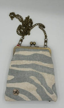 A small fabric crossbody handbag with a light blue and cream zebra stripe pattern, featuring an antique bronze chain strap and a snap button closure, displayed on a white background.