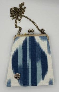 A small crossbody stadium ready purse with a blue and white ikat pattern, antique brass-tone metal frame, and chain strap, shown against a plain white background.