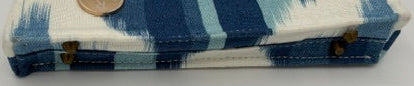A small blue ikat fabric clutch purse with a blue and white ikat stripe pattern, shown on a plain white background with a coin for scale.