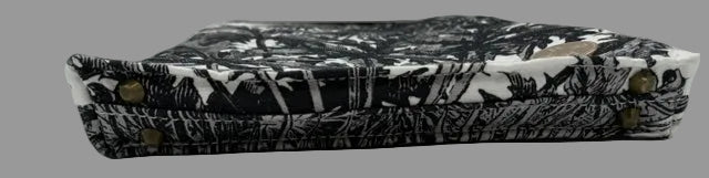 A black and white patterned fabric  small bag with brass-tone metal studs, photographed on a plain white surface.
