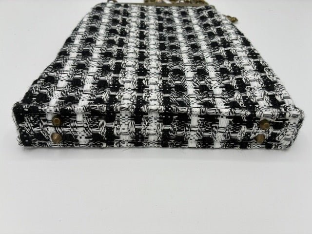 A black and white tweed crossbody purse with a woven pattern and small gold-tone metal studs, shown on a plain white background.