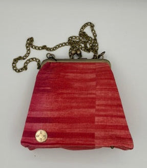 A small coral  striped fabric clutch purse with a gold-tone snap button and a gold-tone chain strap, photographed on a plain white background.