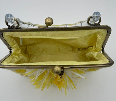 A vintage-style purse with a gold-tone metal frame, yellow satin lining, and yellow tassel fringe, shown open against a plain white background.