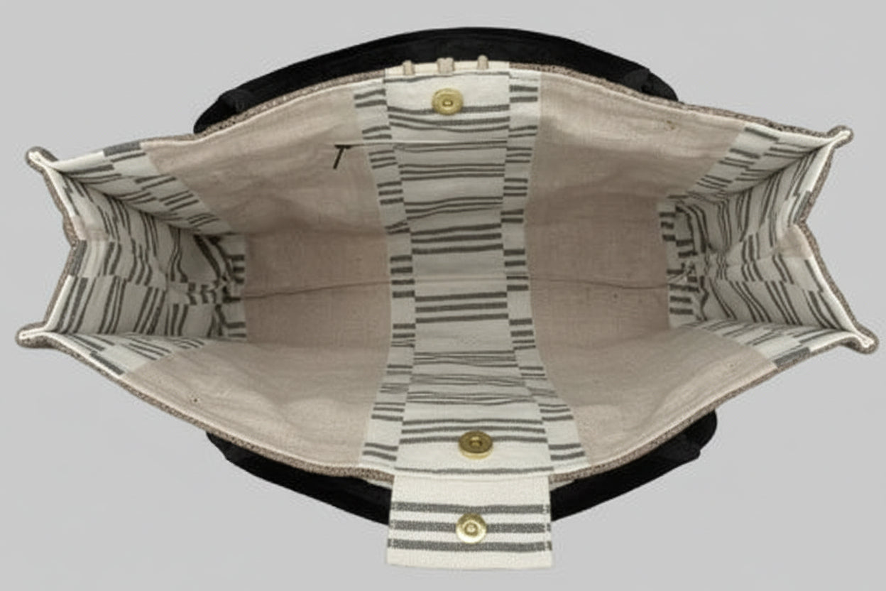 An open canvas tote bag with a striped pattern lining, held by a hand against a white background with black side supports.