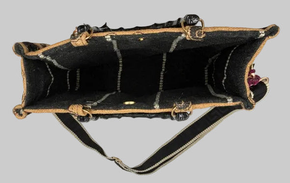 A black wool bag with a textured pattern and tan leather trim, shown from the inside to display the lining and strap attachment.
