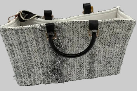 A textured black and white tweed tote bag with black leather handles and gold-tone hardware, shown on a white background.