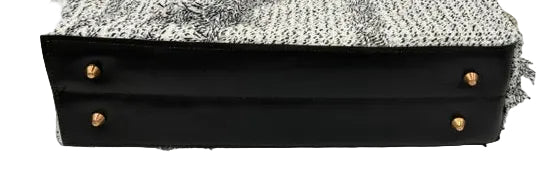 A structured handbag with a black leather base, gold-tone hardware, and a textured black-and-white woven tweed fabric top, set against a black and white studio background.