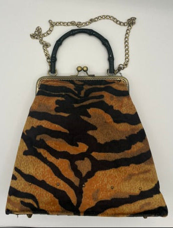 A vintage-style clutch handbag with a tiger-stripe pattern in brown and black, featuring a black leather handle and a silver-tone chain link.