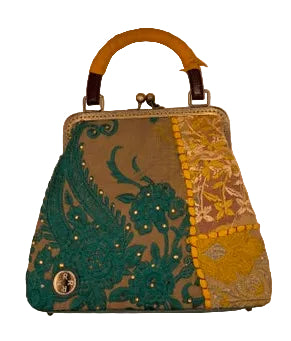 A small structured handbag with a leather wrapped wooden  top handle, featuring a split design with teal paisley embroidery on one side and yellow floral embroidery on the other, set against a plain light background.